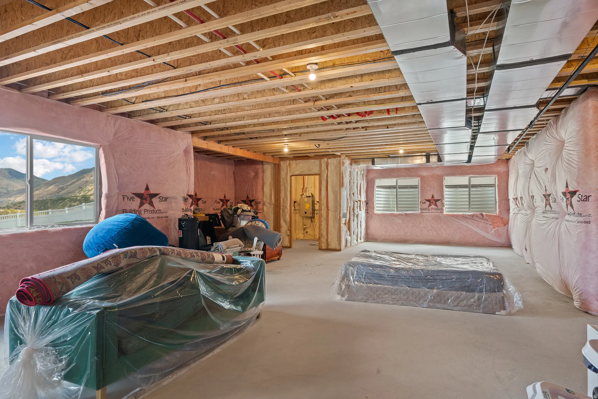 Unfinished lower level featuring exposed ceiling joists, insulated walls, and multiple window openings