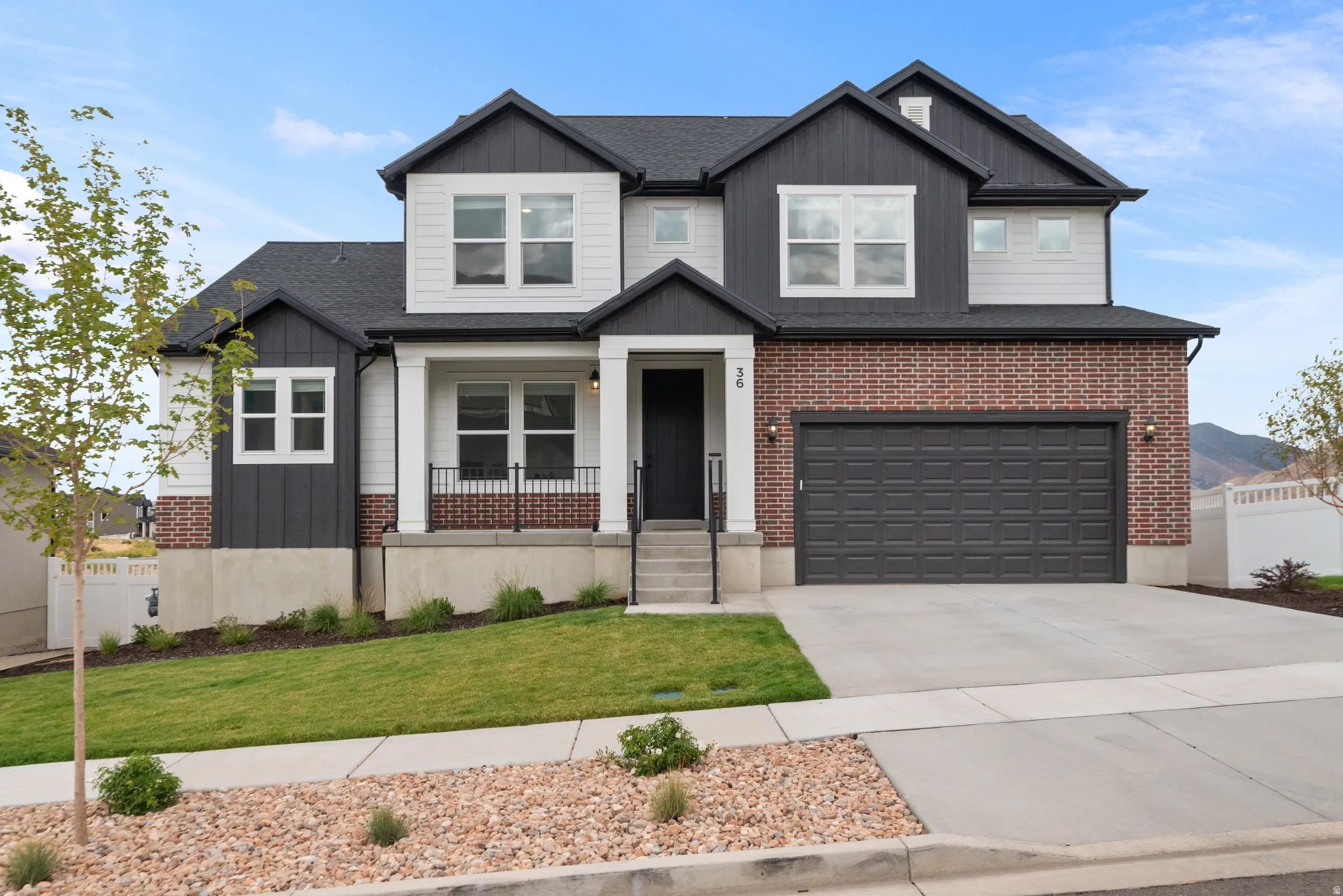 Modern exterior with brick and siding, featuring a covered entry, attached garage, and a concrete driveway