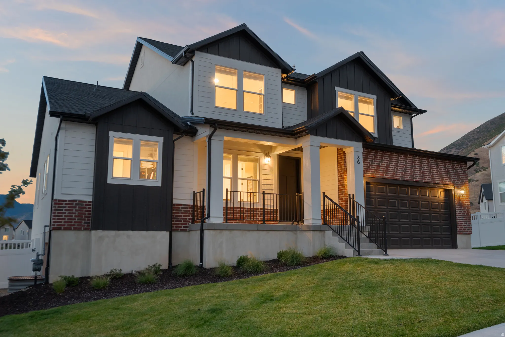 Contemporary two-story exterior with a two-car garage, brick accents, dark siding, and a covered entry