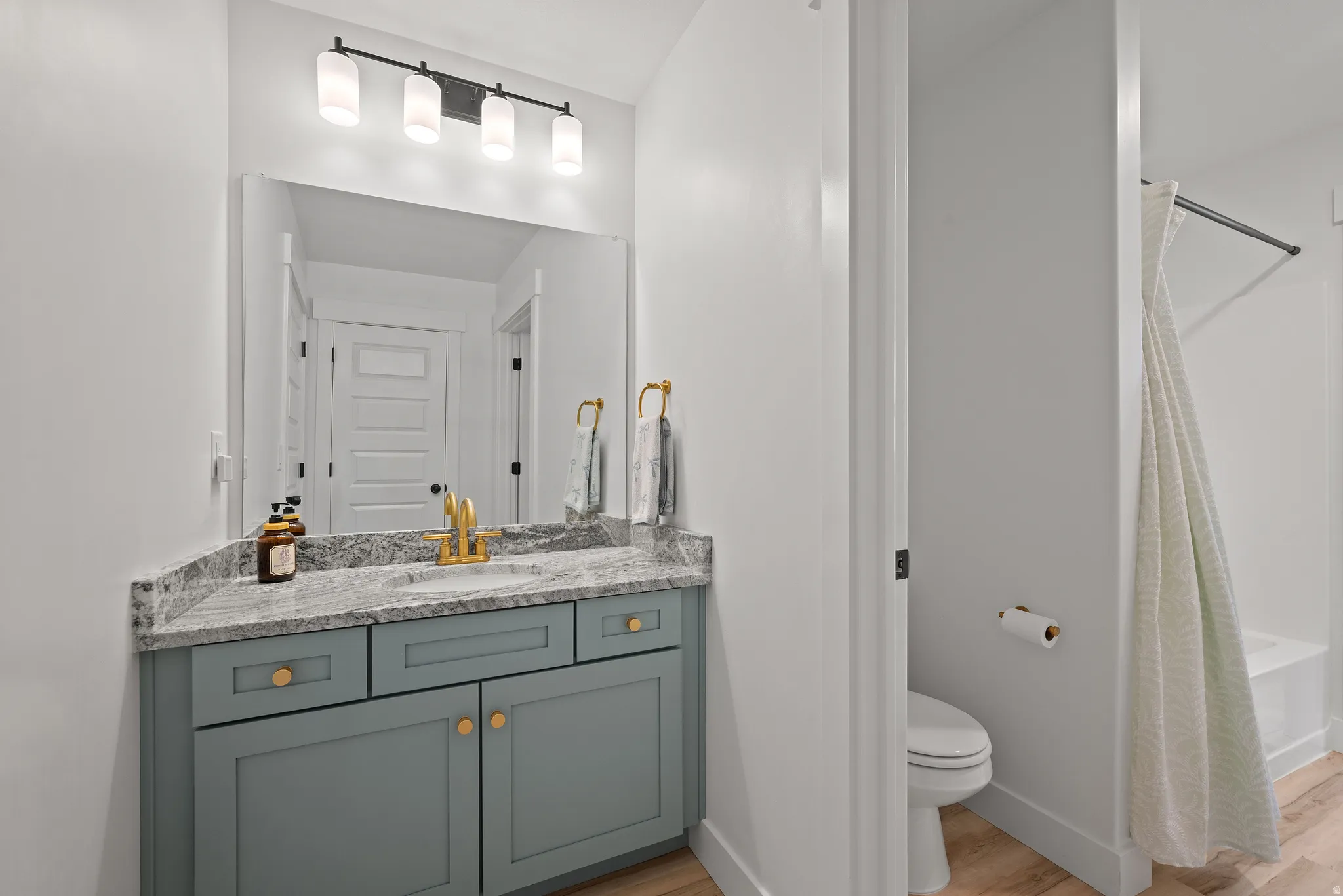 Vanity with a light gray countertop, undermount sink, and brass faucet