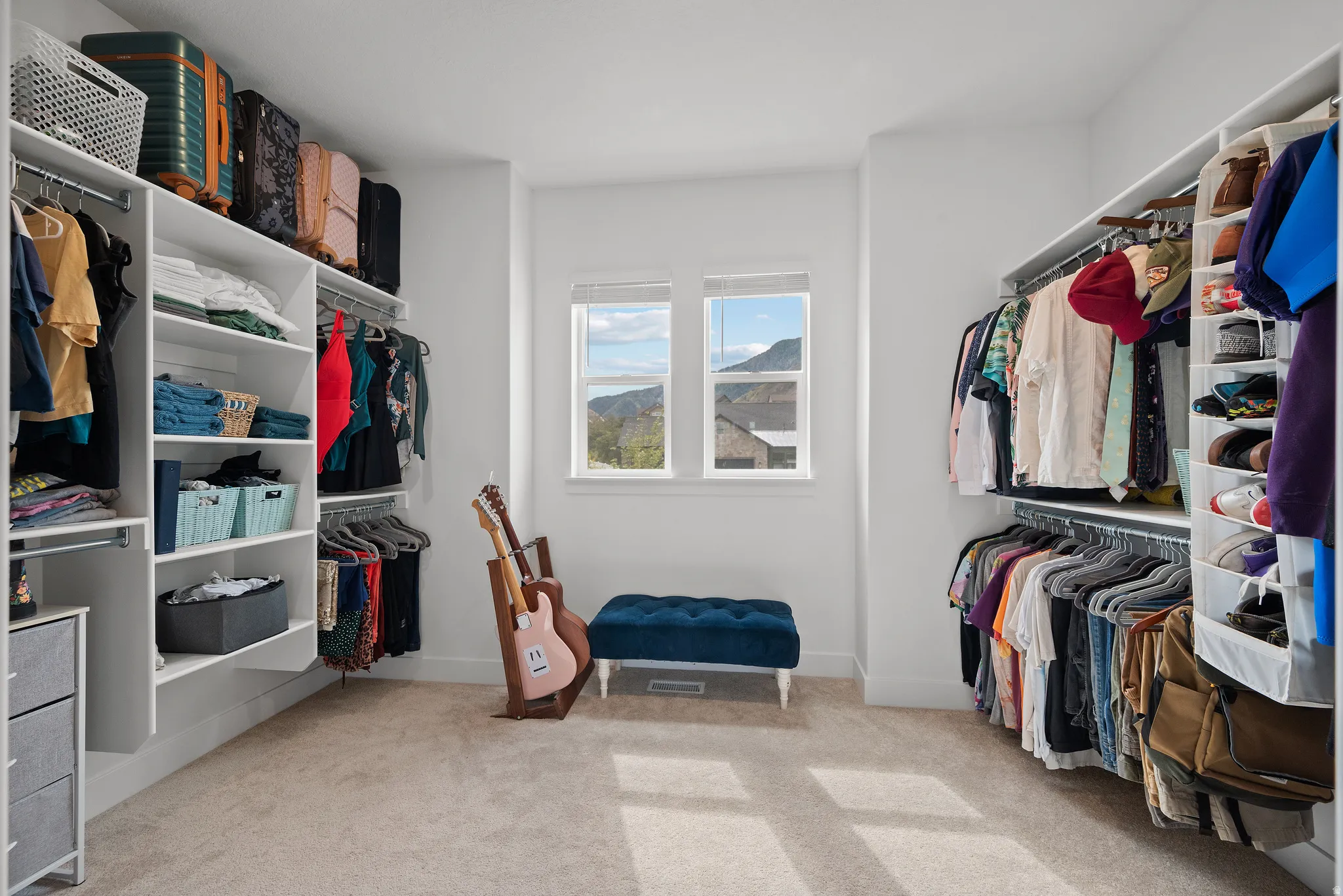 Spacious walk-in closet featuring extensive built-in shelving, multiple hanging rods, and neutral-toned carpeting
