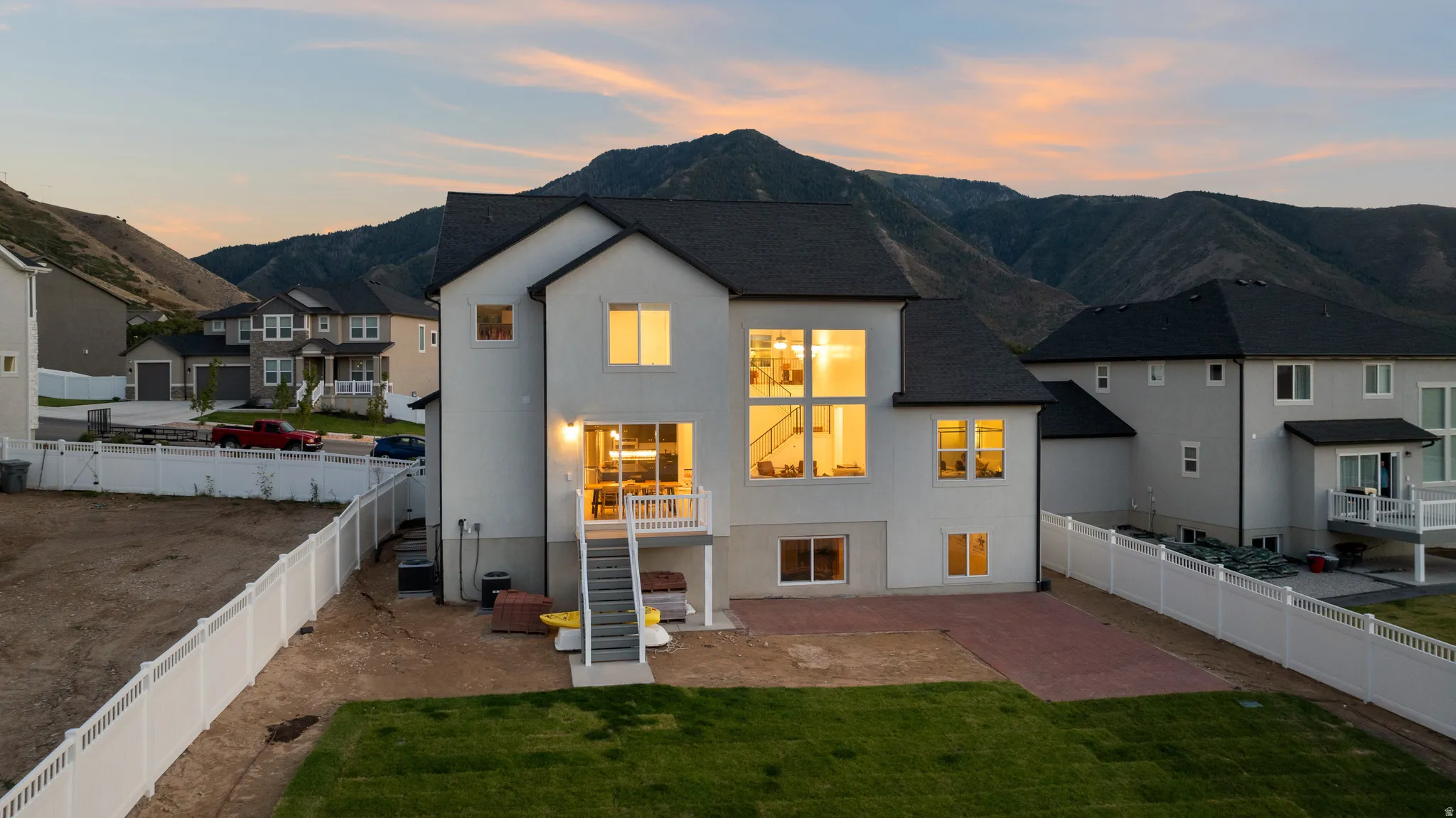 Contemporary two-story residence with a stucco exterior, multiple large windows, and a multi-level deck