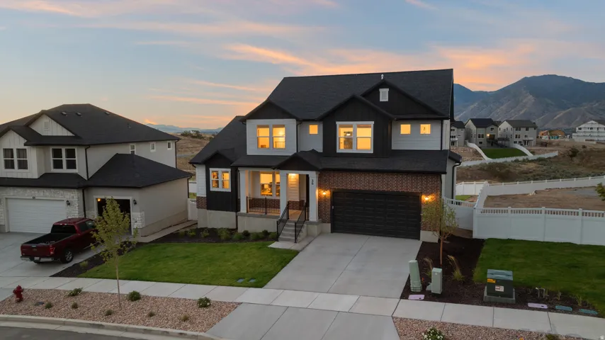 Two-story residence featuring a dark shingle roof, light-colored siding, dark brick accents, and a front-facing garage with a dark door
