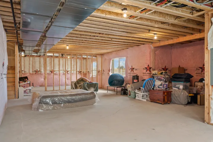 Unfinished basement with exposed wood framing, concrete flooring, and an egress window
