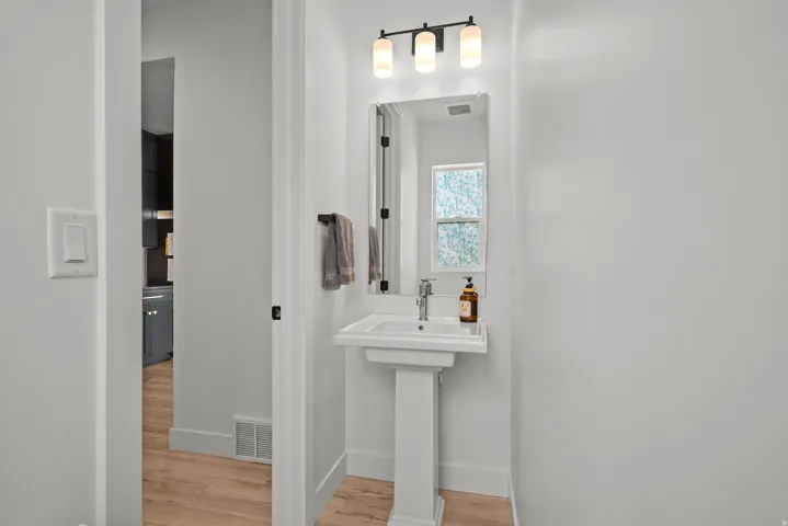 Pedestal sink with chrome faucet, rectangular wall mirror, and matte black vanity light fixture