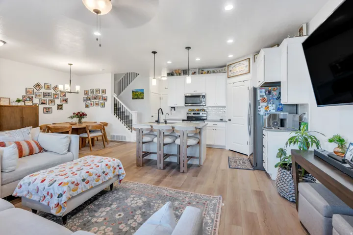 Wood-finish flooring throughout, white kitchen cabinetry, stainless steel appliances, kitchen island with seating, and a dedicated dining area