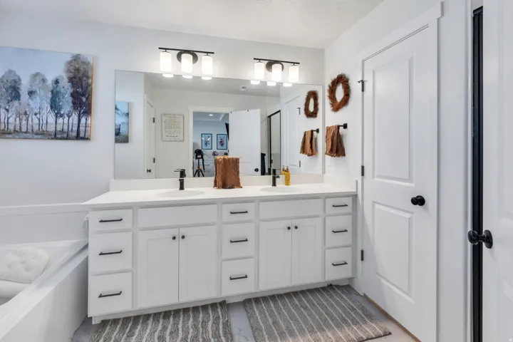Dual vanity with white cabinetry, matte black hardware, and an integrated countertop