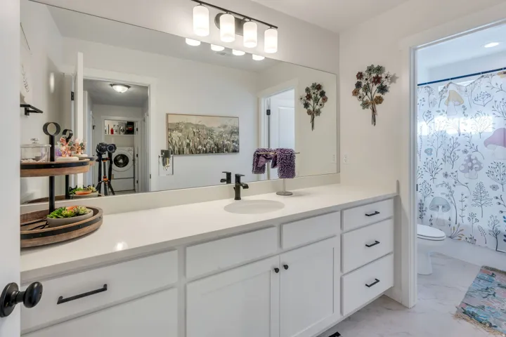 White vanity with integrated sink, matte black faucet, and coordinating hardware