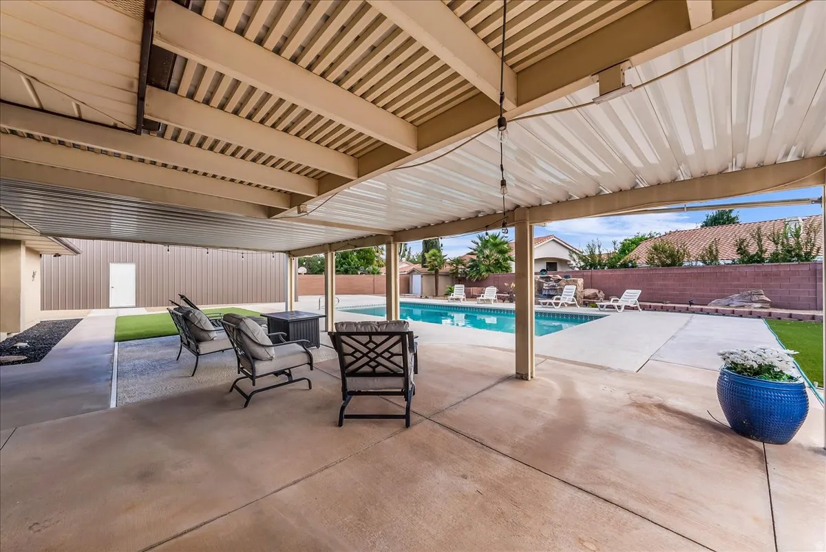 Covered patio with a concrete surface, a built-in swimming pool, a rock waterfall feature, and artificial turf sections