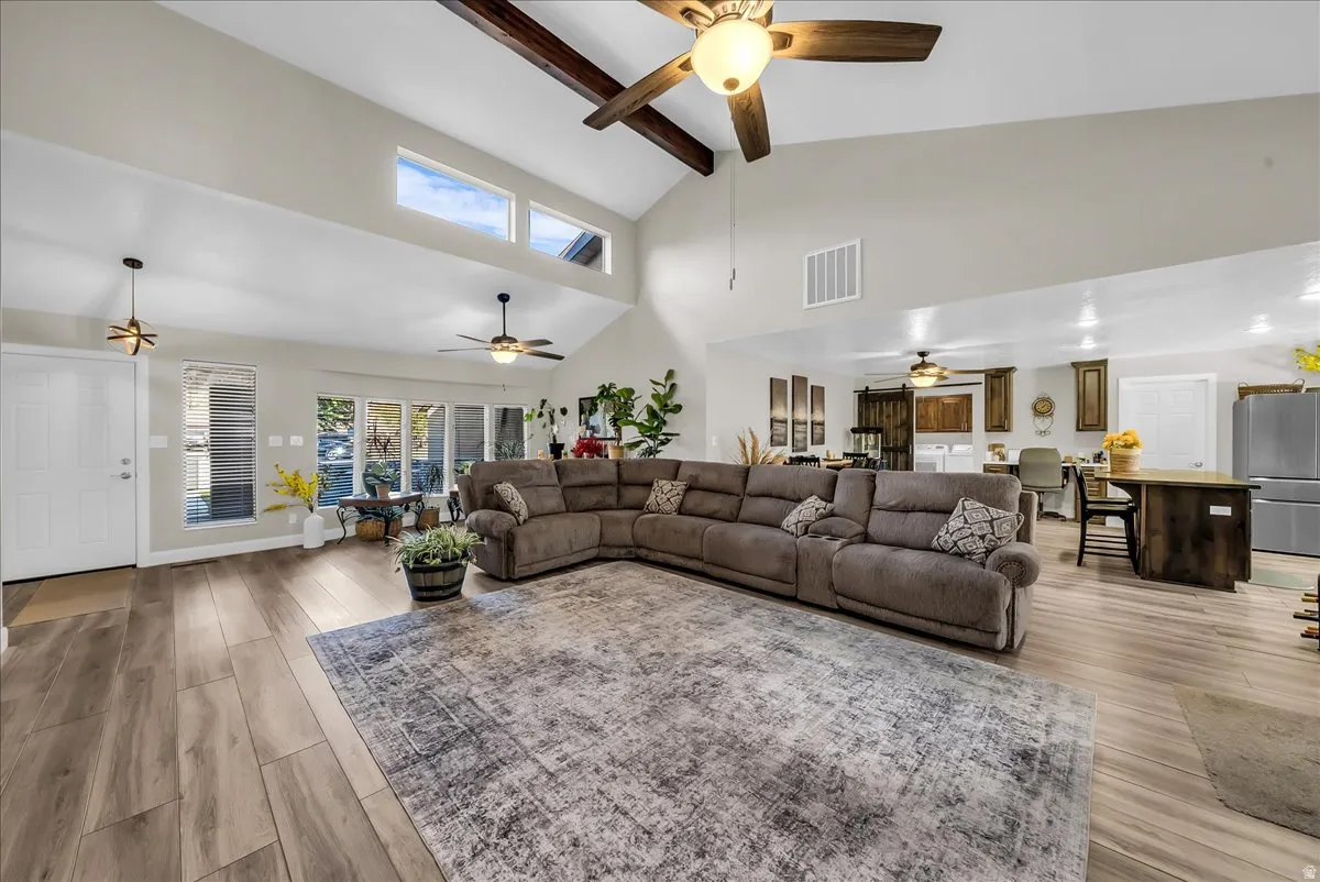 Vaulted ceilings with exposed wood beams, wood-finish flooring, abundant natural light, and an open-concept layout
