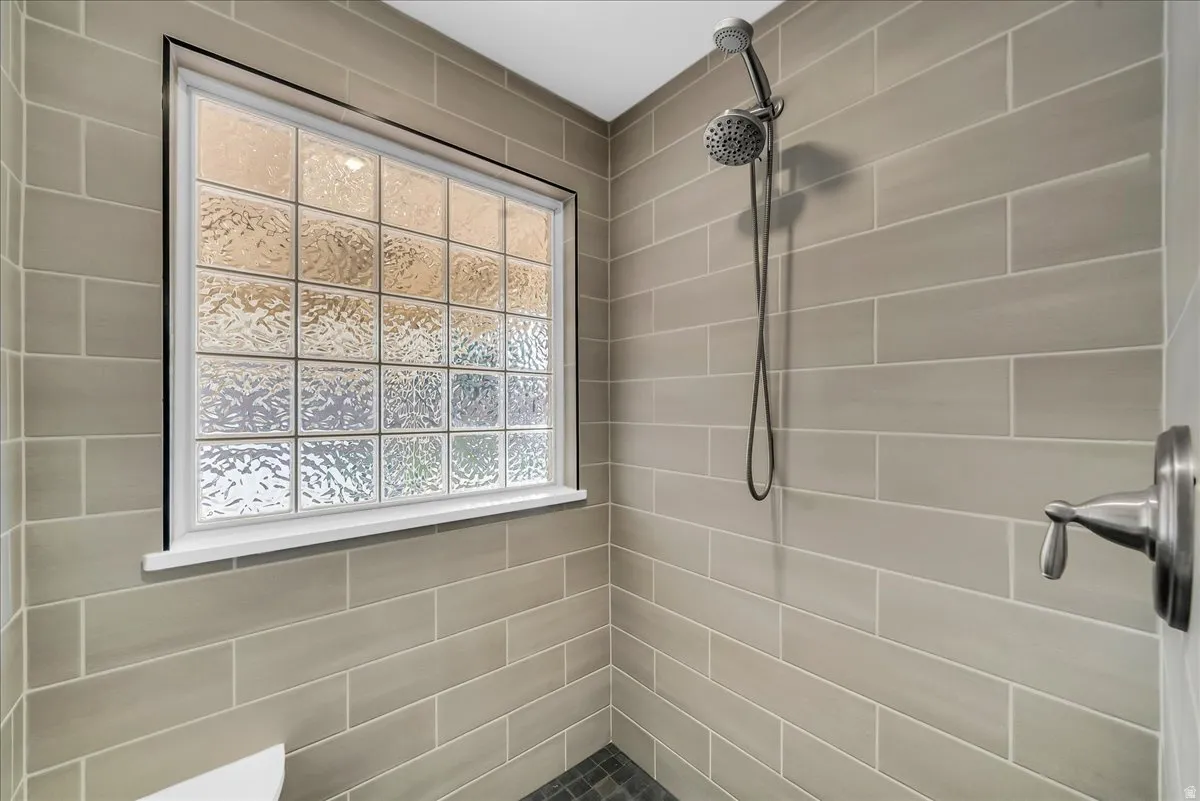 Glass block window with white trim, subway tile walls, dark-toned floor tile, and a brushed nickel shower fixture