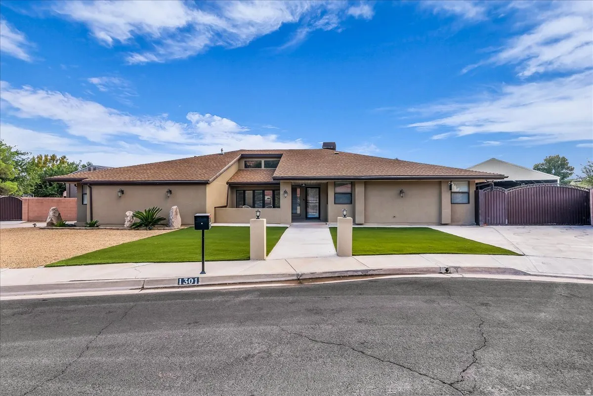 Single-story residence featuring stucco exterior, a brown shingle roof, and an integrated two-car driveway