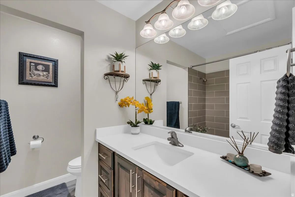 Single vanity with a white countertop and integrated sink, dark wood-finish cabinetry, and a chrome faucet