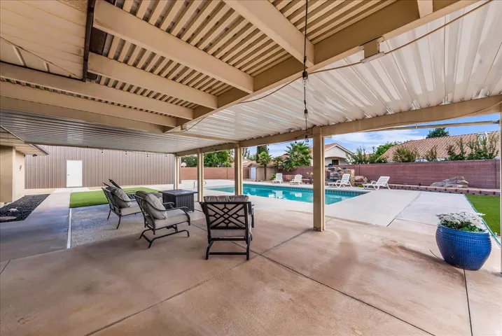 Covered patio with a concrete surface, a built-in swimming pool, a rock waterfall feature, and artificial turf sections