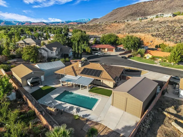 In-ground swimming pool, solar panels, dedicated outbuilding, covered patio, and mountain backdrop