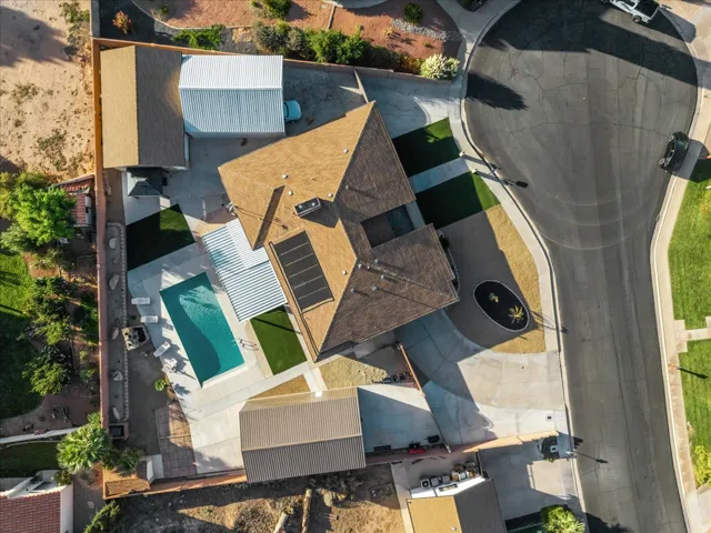 Swimming pool with concrete surround, synthetic turf accents, solar panels, and a detached auxiliary structure