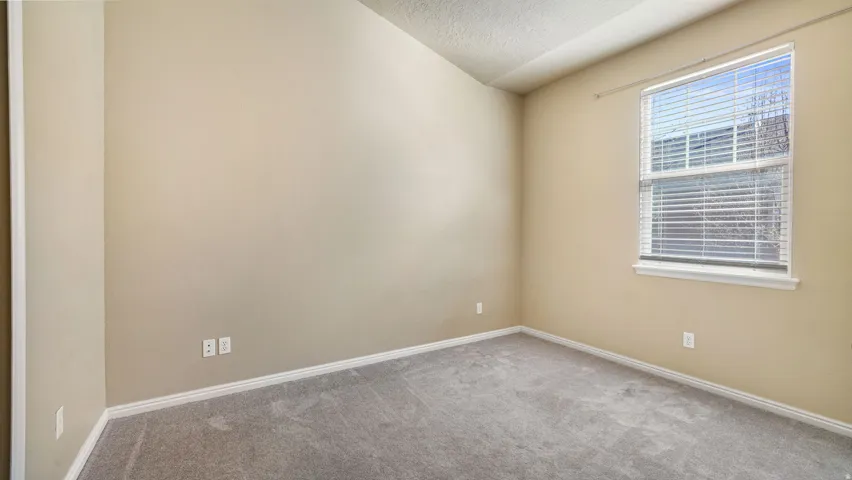 Neutral-toned walls, gray carpet flooring, white trim, and a window with horizontal blinds