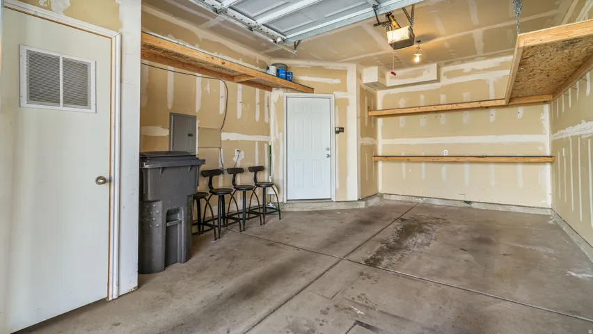 Concrete floor, built-in overhead storage shelves, built-in wall shelving, two entry doors, exposed drywall