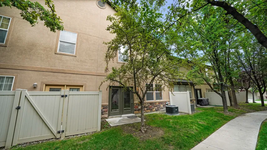 Stucco exterior with stone accents, a private fenced patio, and a mature tree