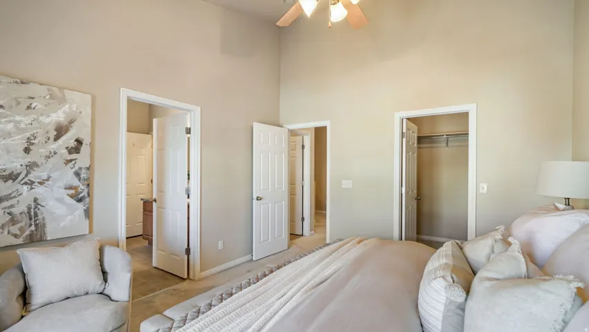 Vaulted ceiling with a ceiling fan, carpet flooring, multiple panel doors, and a closet with shelving and a hanging rod