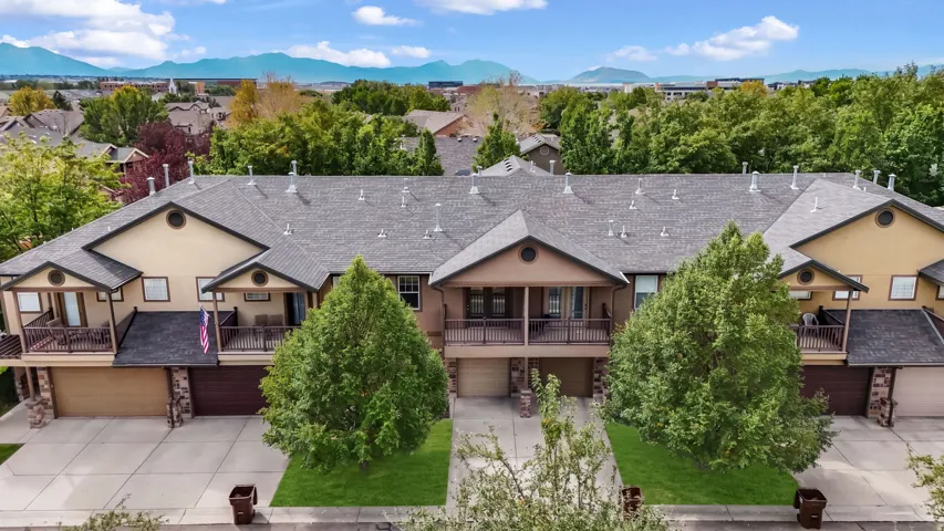 Multi-unit property featuring an asphalt shingle roof, attached garages, stone facade accents, and covered balconies