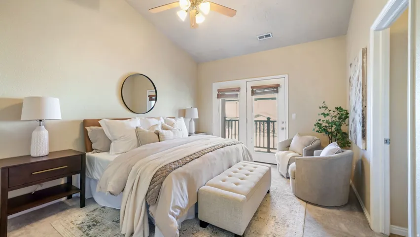 Vaulted ceiling with ceiling fan, double French doors, and dark wood-finish nightstands