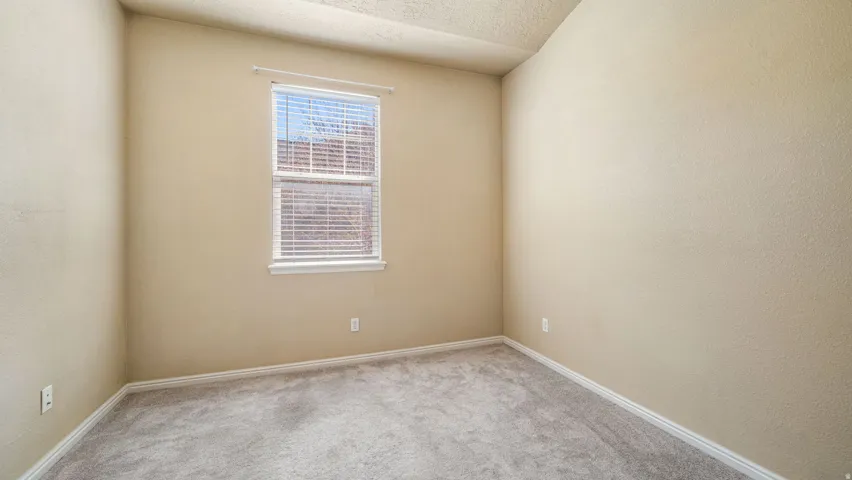 Neutral tone wall paint, textured ceiling, and a double-hung window with blinds