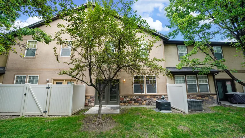 Stucco exterior with stone accent detailing, featuring multiple windows and a private fenced patio area
