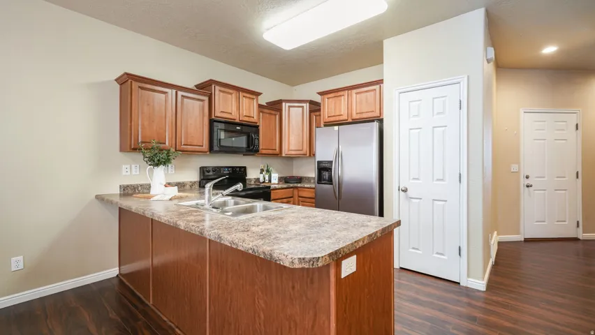 Kitchen featuring wood-finish flooring, wood cabinetry, built-in microwave, and stainless steel refrigerator