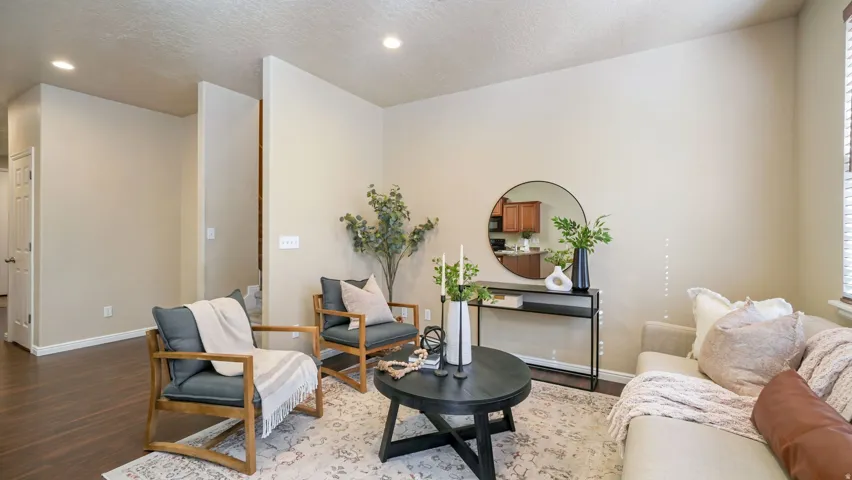 Recessed lighting illuminates the living area with wood-finish flooring and light-toned walls