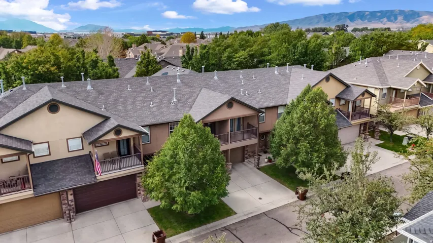 Townhome exterior with attached garages, individual balconies, and mature landscaping