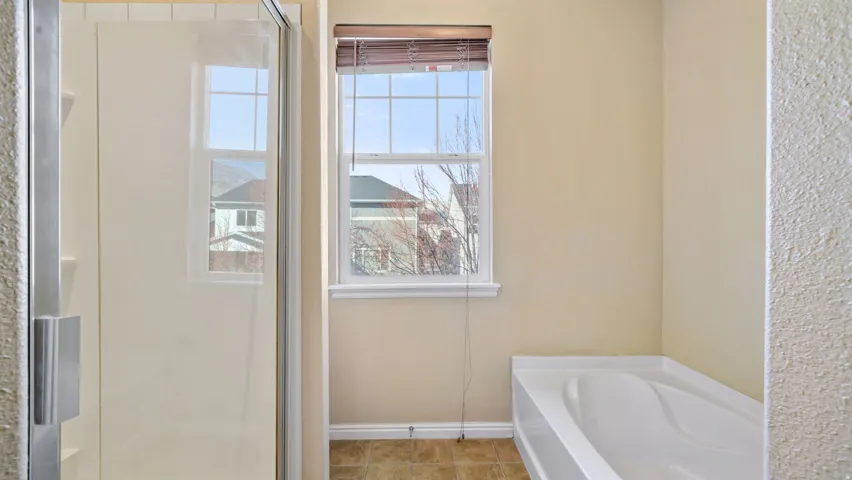 Shower enclosure with clear glass door, built-in shelving, and white tile surround