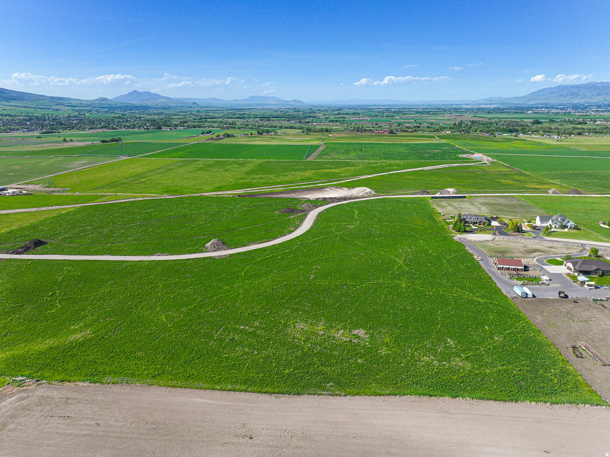 Expansive green lot with a gravel path and distant mountain scenery