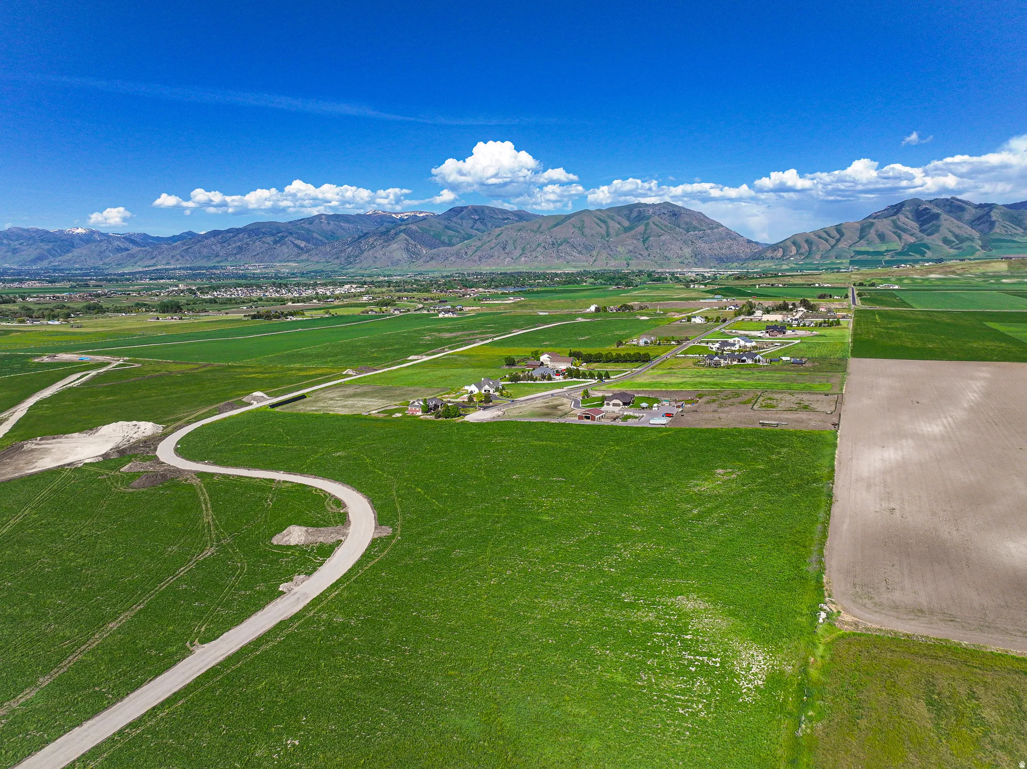 Expansive green fields with distant mountains and scattered residential properties