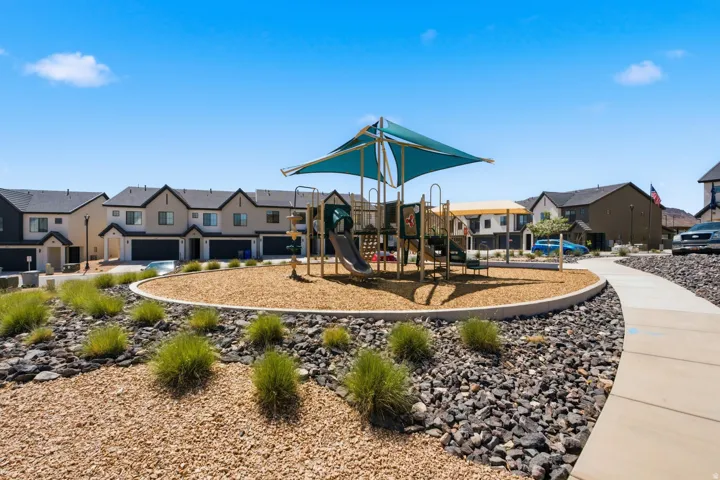 Community playground with shade canopy, wood chip surfacing, and surrounding landscaped areas