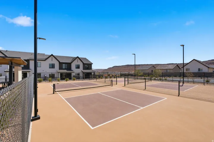 Multiple pickleball courts with perimeter fencing, integrated lighting, and surrounding residential structures