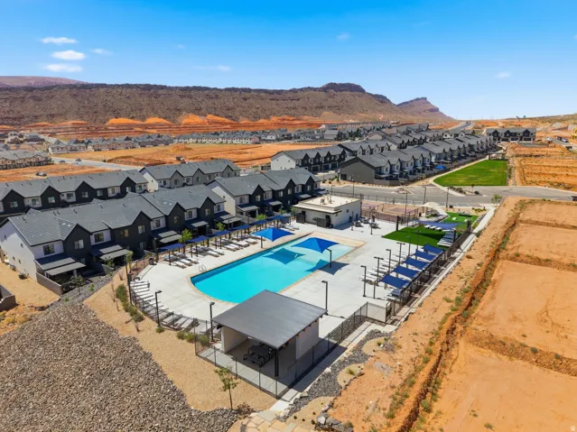 Community swimming pool with a surrounding patio, multiple chaise lounges, and shaded seating areas
