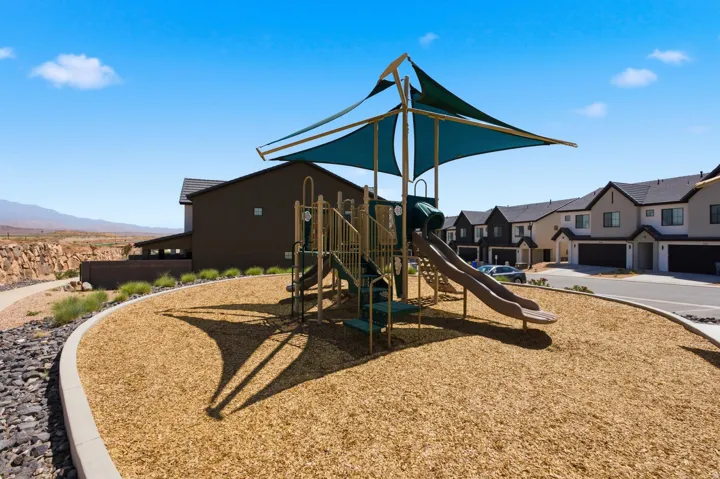 Community playground featuring a shade structure and wood chip surfacing
