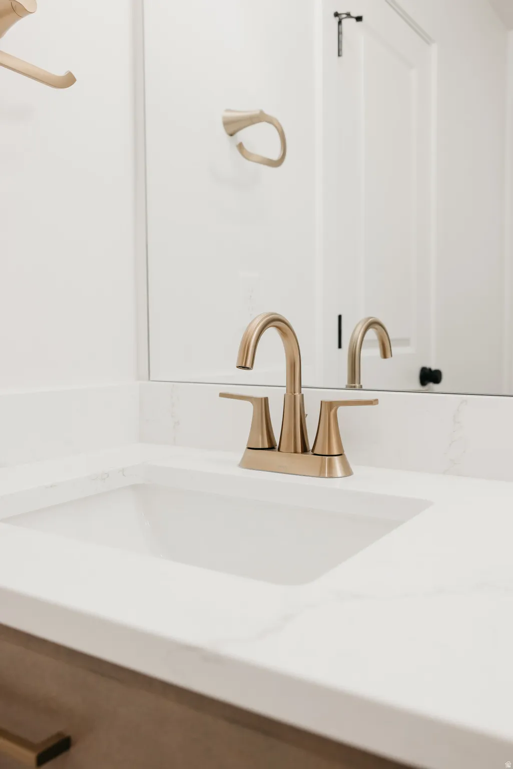 White countertop with integrated sink, brushed gold-finish faucet, and coordinating towel ring