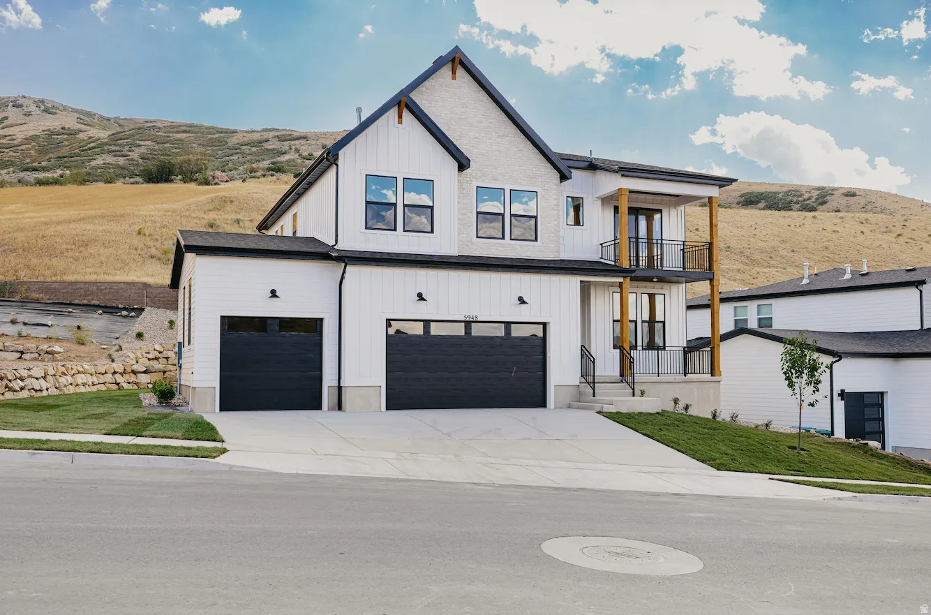 Modern two-story residence featuring a white board and batten facade, black-framed windows, and a two-car garage with dark paneled doors