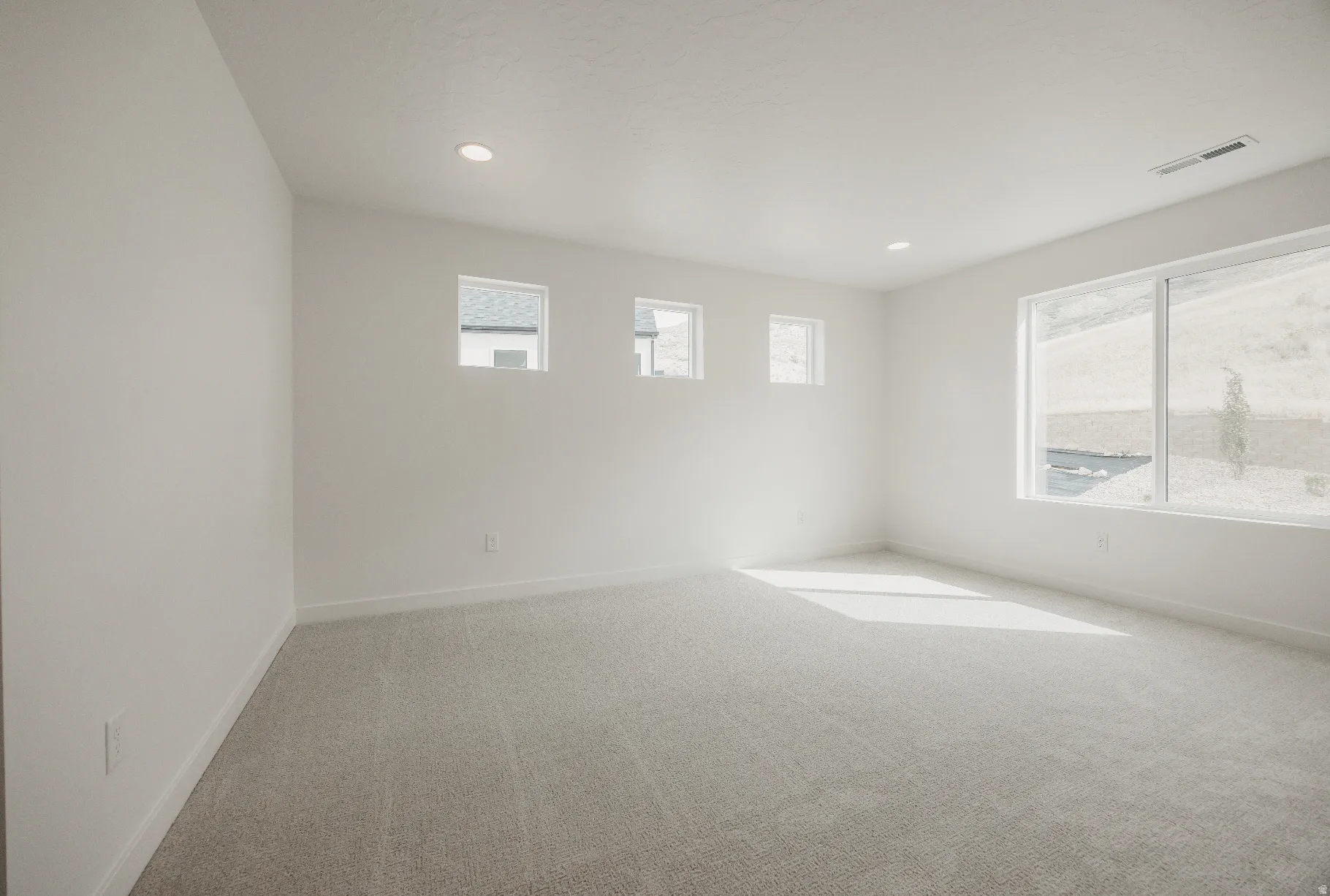 Expansive room featuring light gray carpeting and white walls