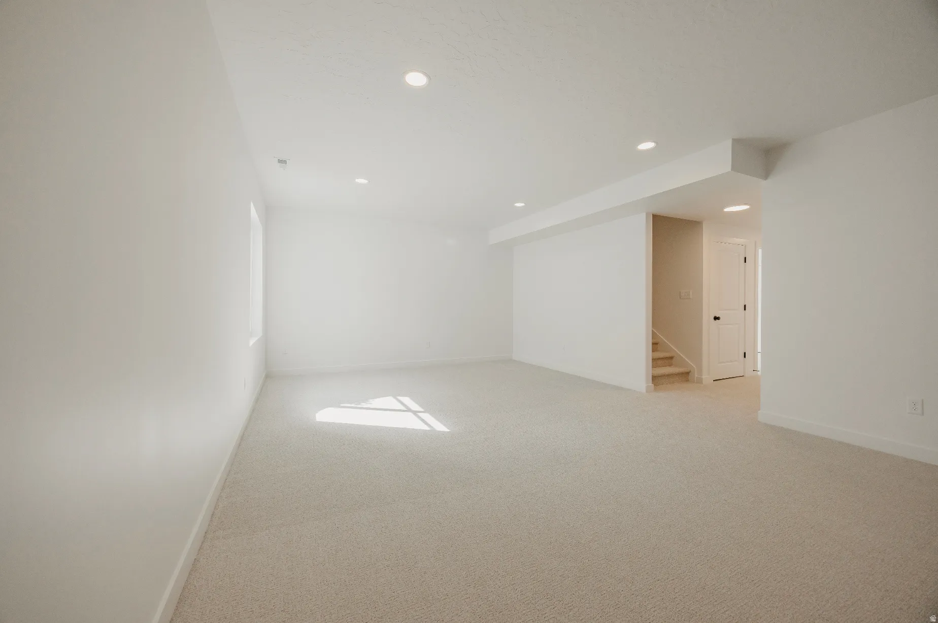Recessed lighting, light-colored carpeting, white interior walls, interior staircase, white interior door with black hardware