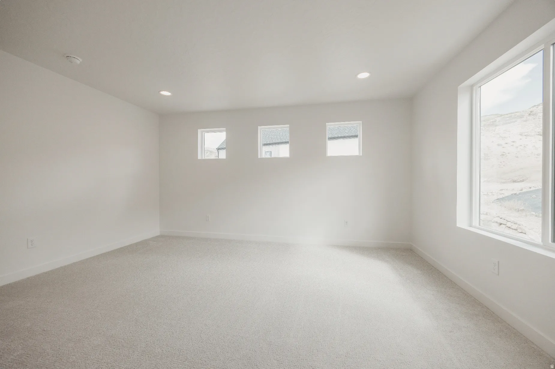 Recessed ceiling lighting, light-colored carpeting, multiple windows, and crisp white walls