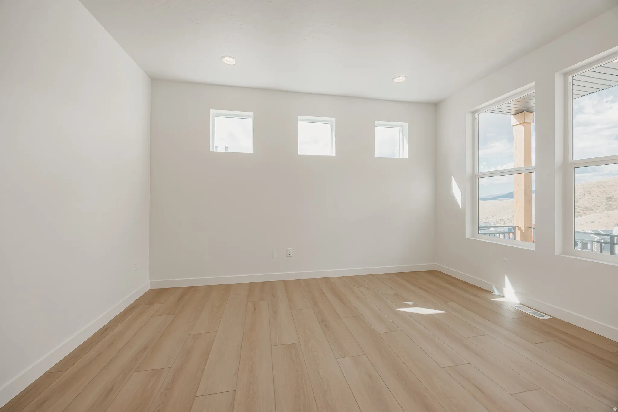Bright interior with multiple windows, recessed ceiling lighting, and wood-finish flooring