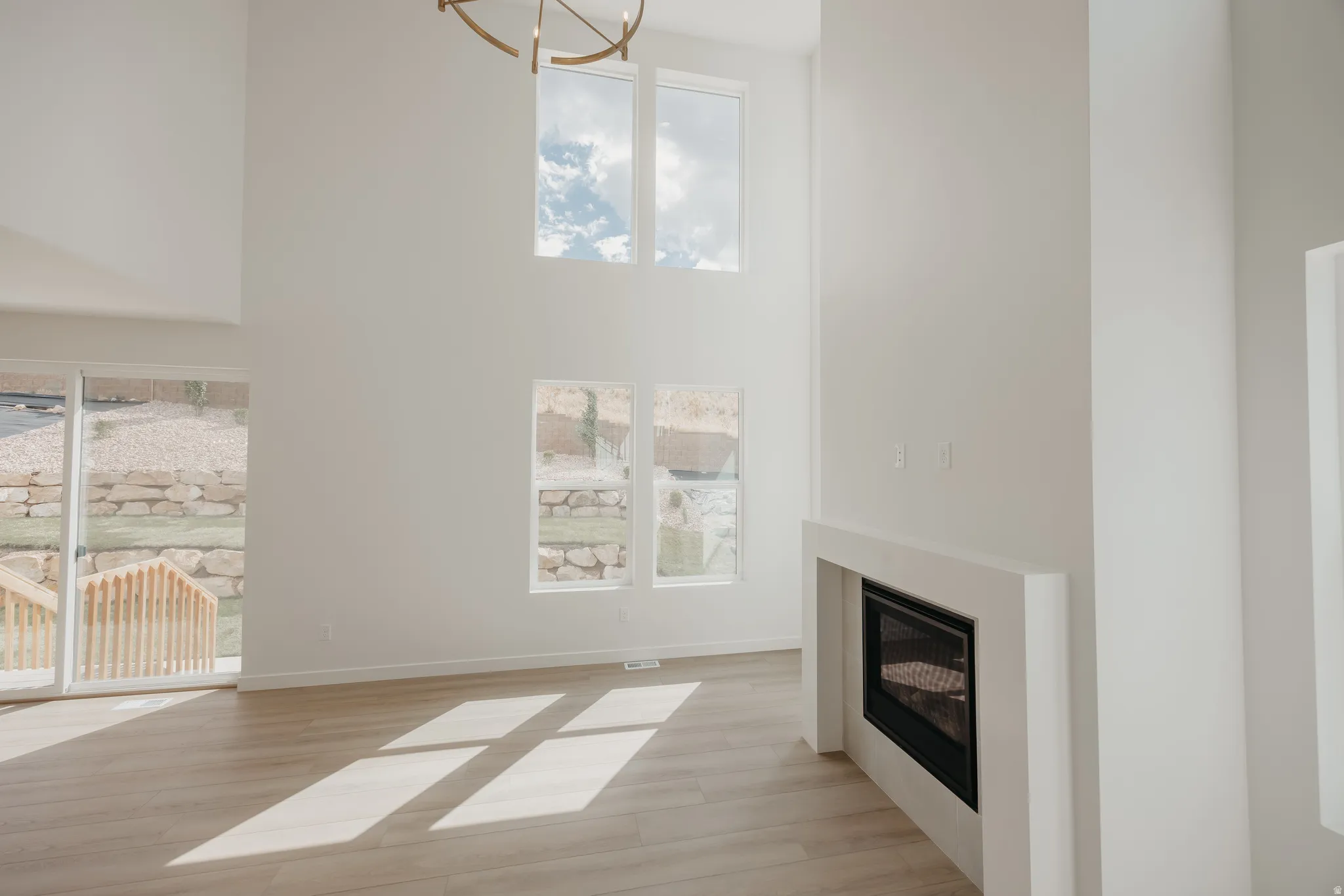 Soaring ceilings, abundant natural light, recessed fireplace, wood-finish flooring, and a contemporary light fixture
