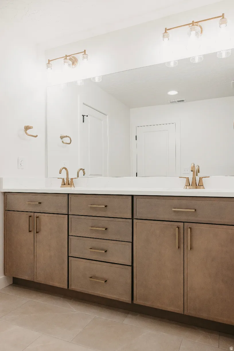 Dual vanity featuring a white countertop, wood-finish cabinetry, and gold-tone fixtures