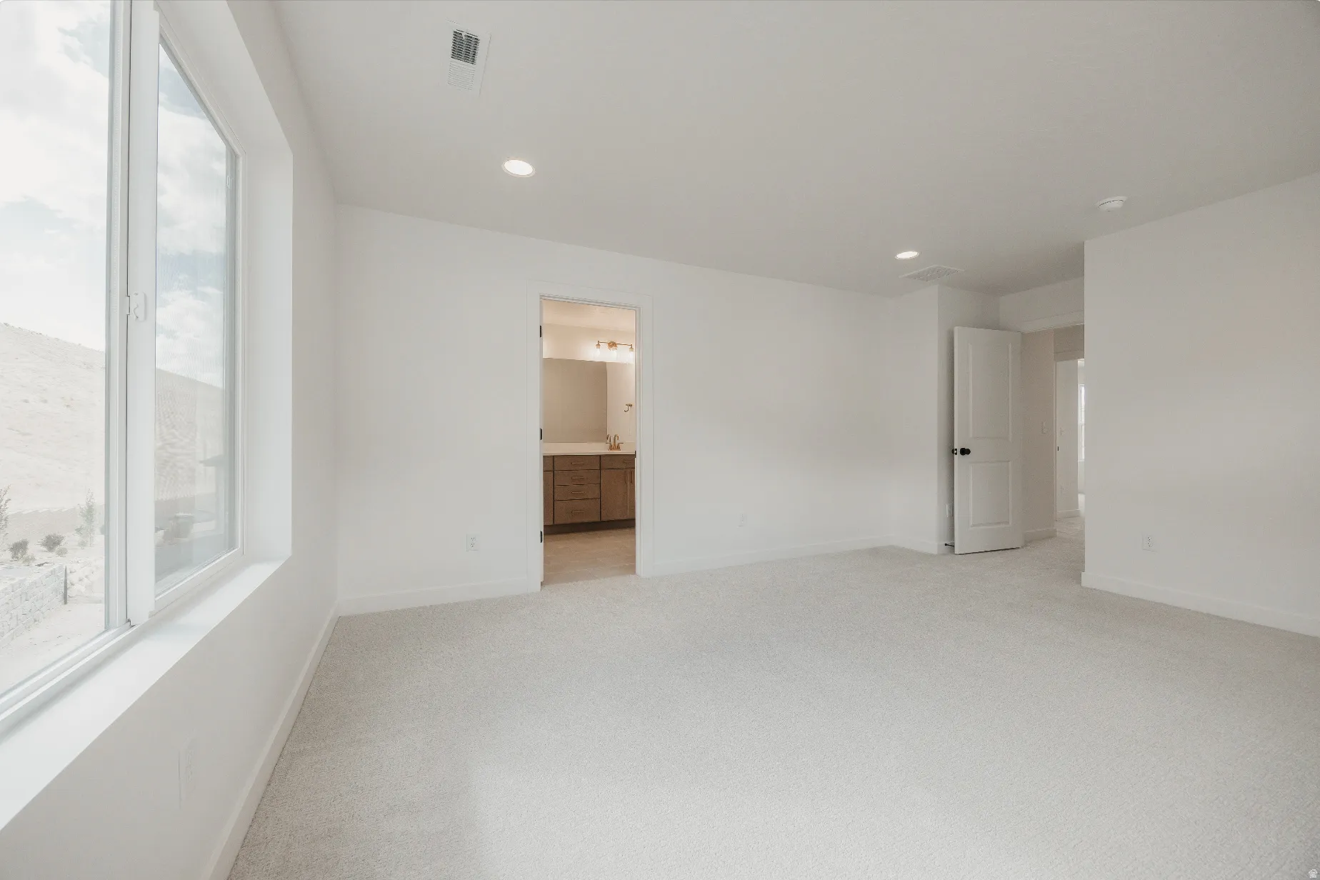 Recessed ceiling lighting, light-toned carpet, white walls, and a large window