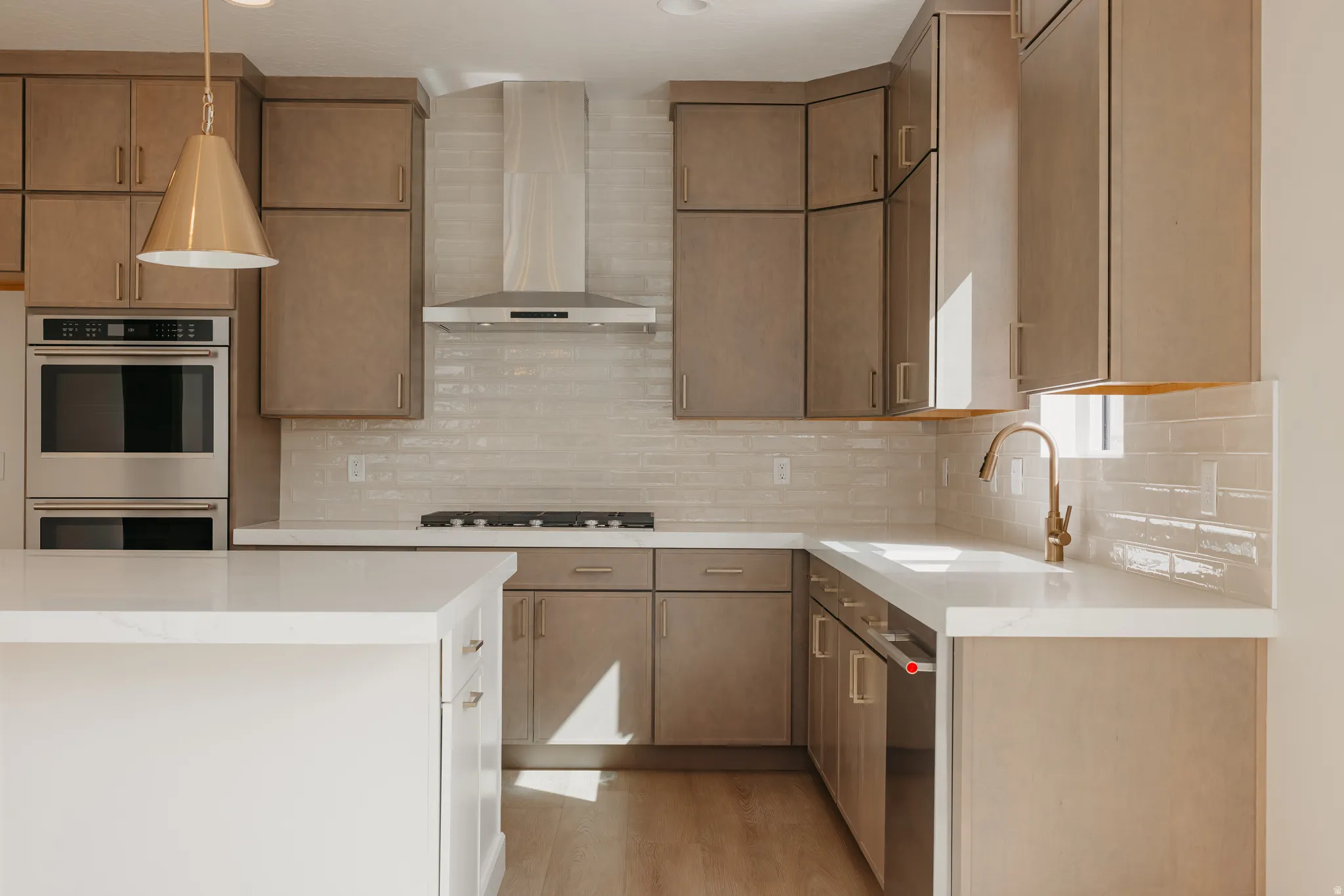 Kitchen featuring stainless steel appliances, a built-in double oven, a gas cooktop, a stainless steel range hood, and a light-toned tile backsplash