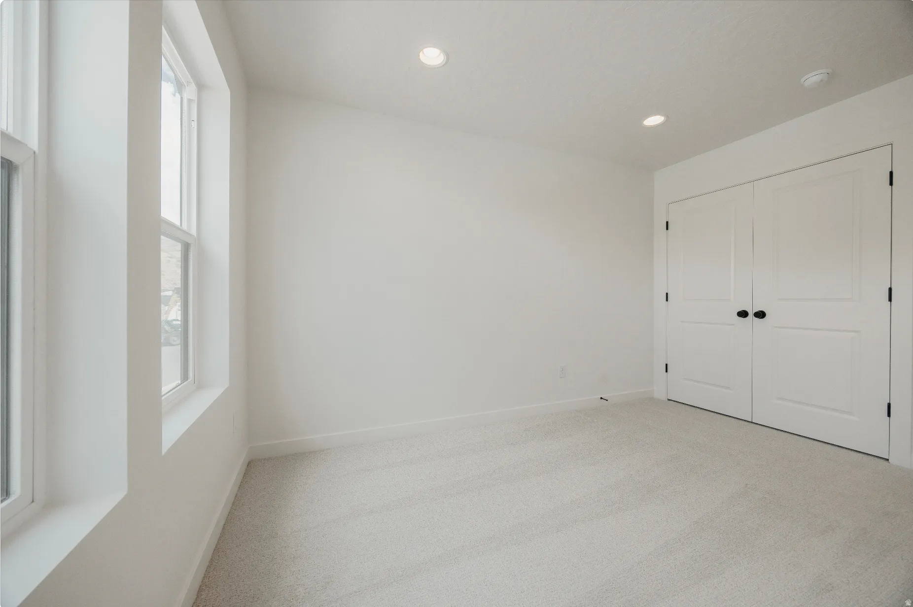 Double windows with white trim, recessed lighting, and light-toned carpeting