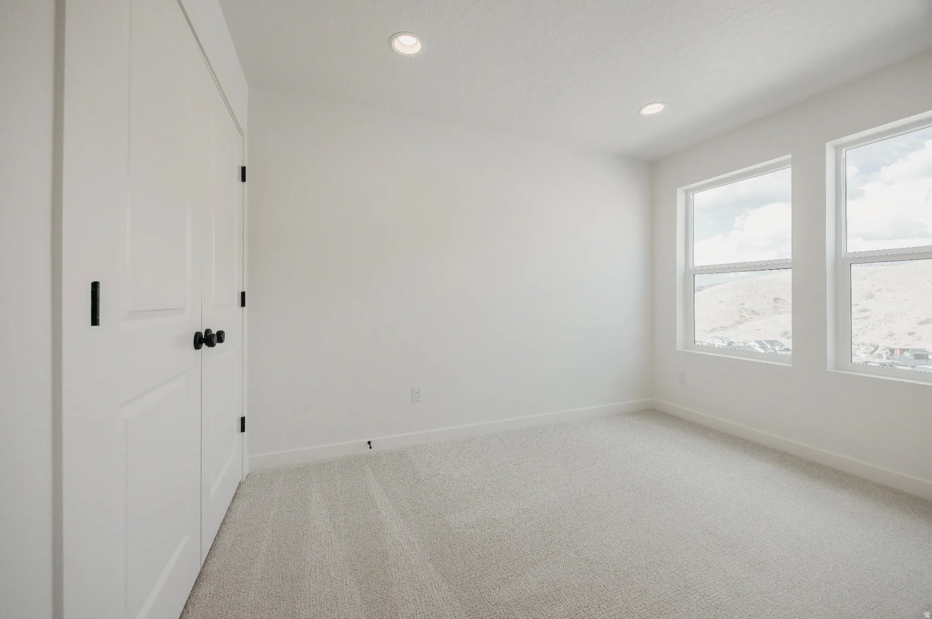 White walls, two windows, recessed lighting, white trim, and light gray carpeting